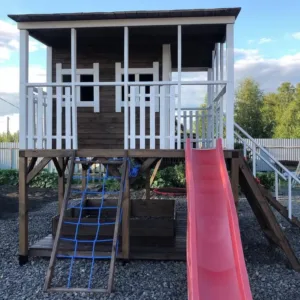 Wooden playhouse with slide and climbing wall