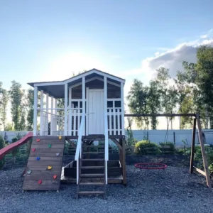 Wooden playhouse with slide and climbing wall